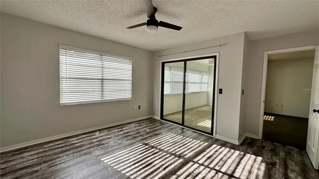 a view of an empty room with window wooden floor and a chandelier fan