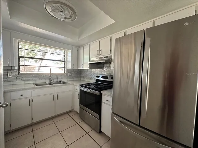 a kitchen with stainless steel appliances granite countertop a refrigerator sink and stove