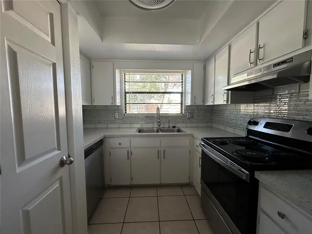 a kitchen with granite countertop a sink stove and refrigerator