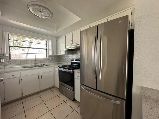a kitchen with granite countertop stainless steel appliances a refrigerator sink and cabinets