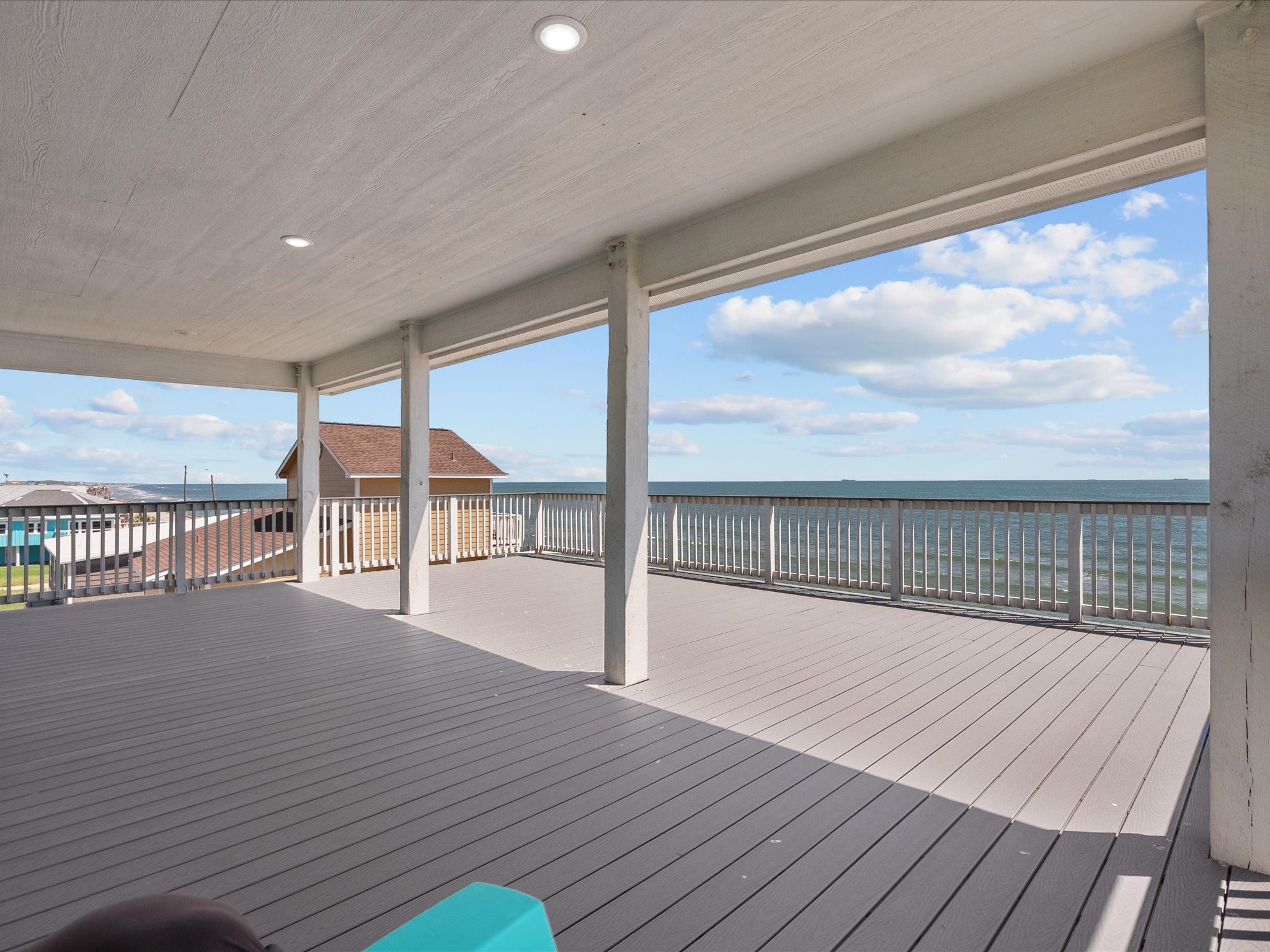 718 Beach Drive Surfside Beach, TX 77541 - Photo 43 of 49 Expansive covered deck with wooden floors, ideal for outdoor gatherings. Includes a picnic table, seating area, and large windows with serene neighborhood views.