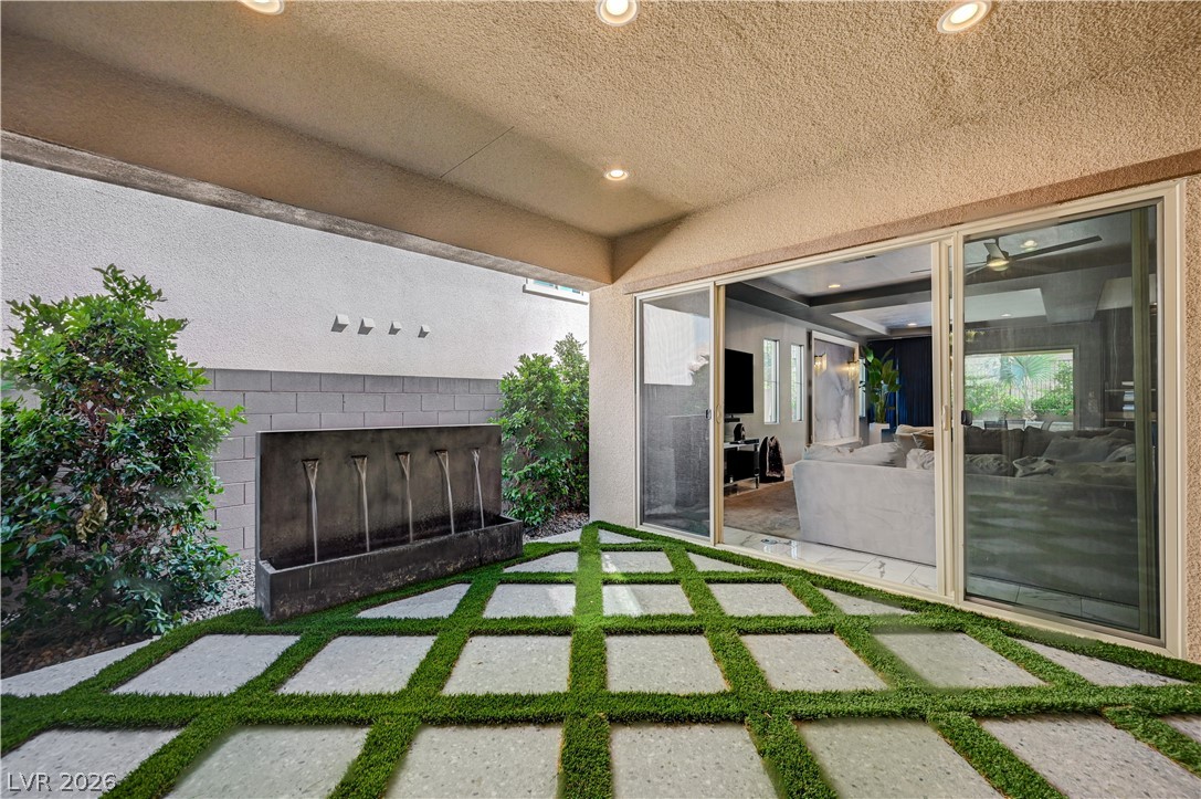 3943 Reyes Avenue Las Vegas, NV 89141 - Photo 49 of 95 A stylish patio features a modern water feature and lush green squares interspersed with stone pavers.