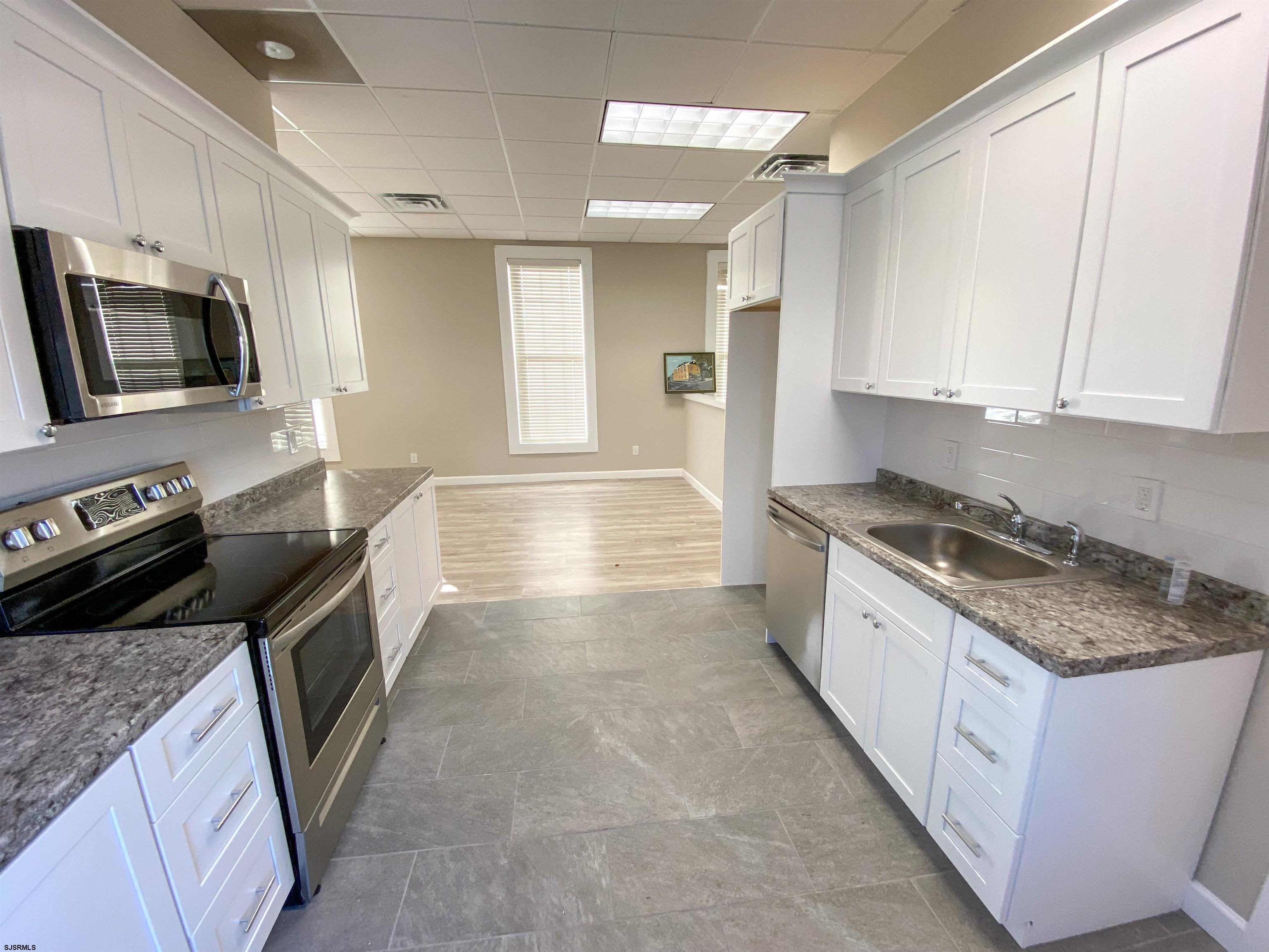 6019 Main Street, Unit 2 Mays Landing, NJ 08330 - Photo 5 of 26 a kitchen with stainless steel appliances granite countertop a stove a sink and a microwave
