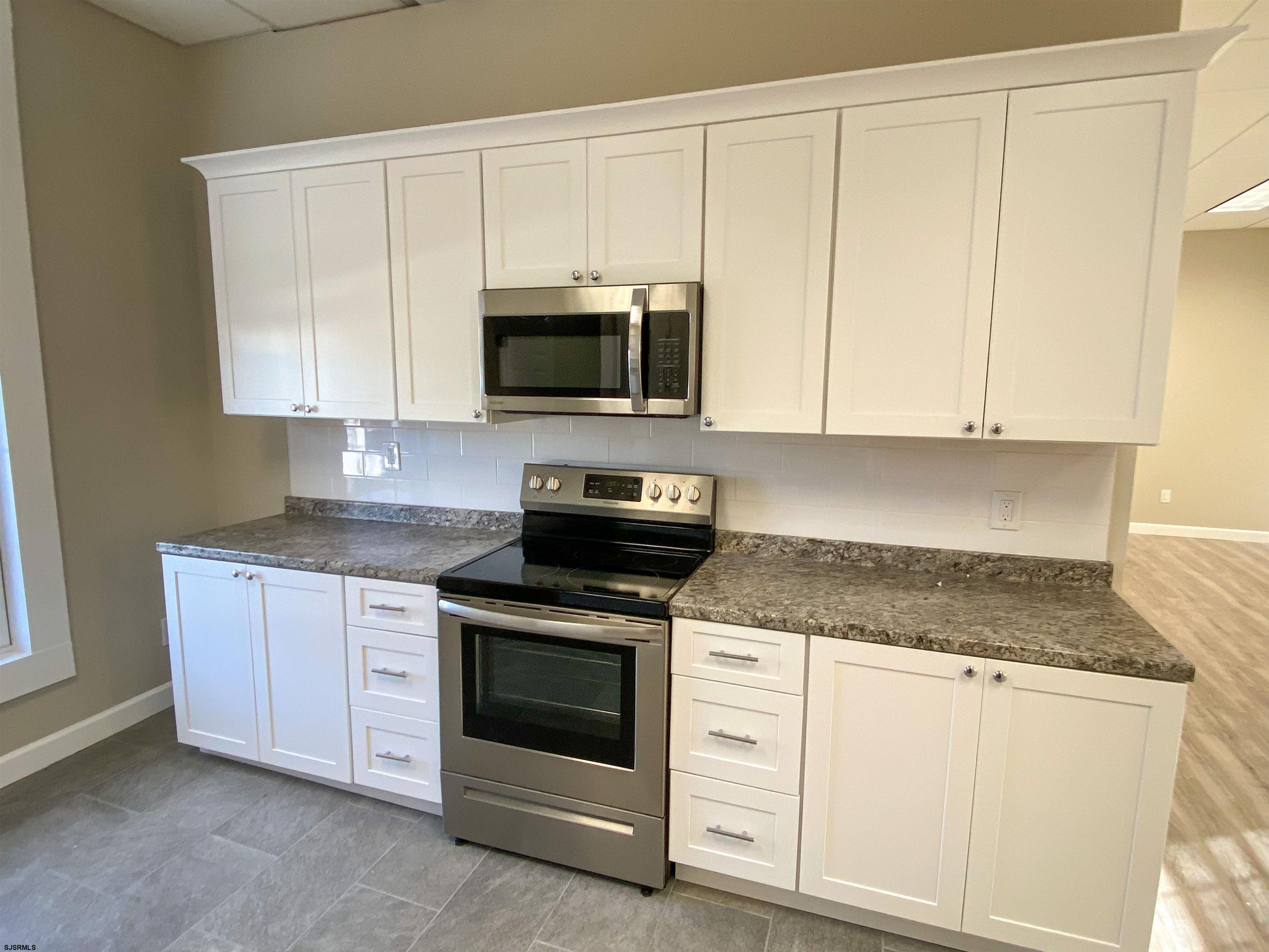 6019 Main Street, Unit 2 Mays Landing, NJ 08330 - Photo 9 of 26 a kitchen with granite countertop white cabinets and stainless steel appliances