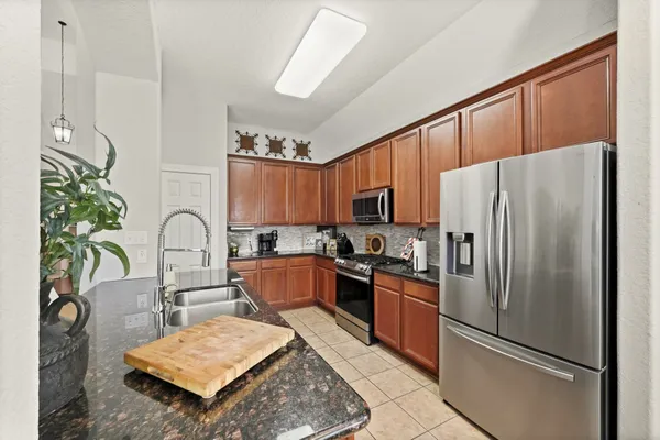 a kitchen with stainless steel appliances a refrigerator a stove a sink cabinets and a dining table