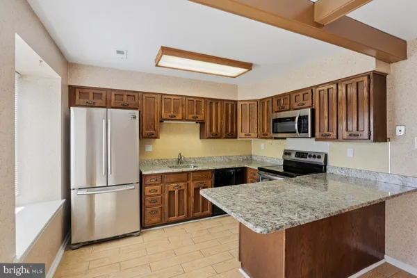 a kitchen with stainless steel appliances granite countertop a sink dishwasher stove top oven and refrigerator