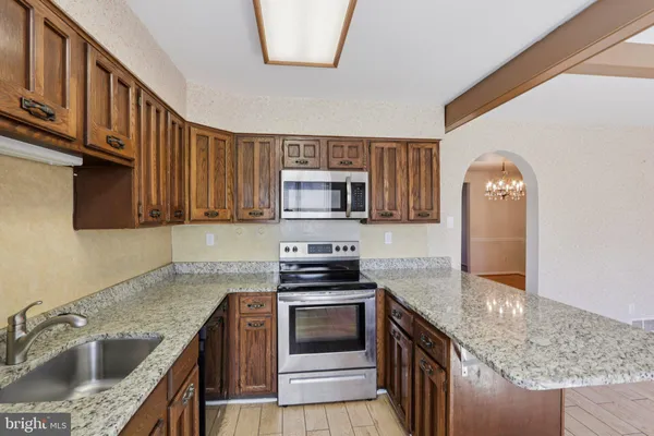 a kitchen with granite countertop a sink a stove and cabinets