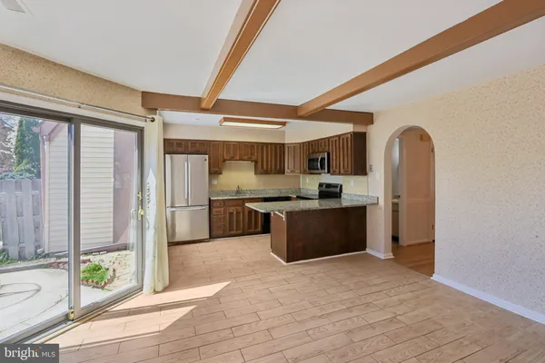 a kitchen with stainless steel appliances kitchen island granite countertop a refrigerator a sink and a dishwasher with wooden floor