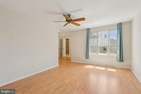 a view of empty room with wooden floor and fan