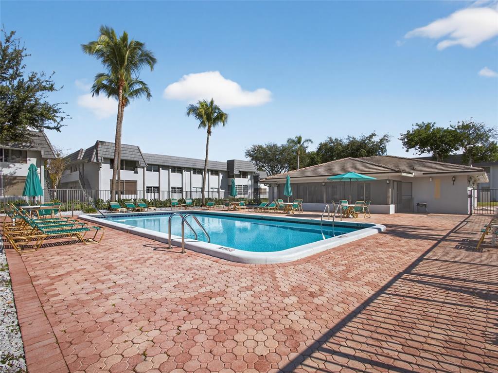 8400 West Sample Road, Unit 203 Coral Springs, FL 33065 - Photo 24 of 26 a view of a swimming pool with a yard and plants