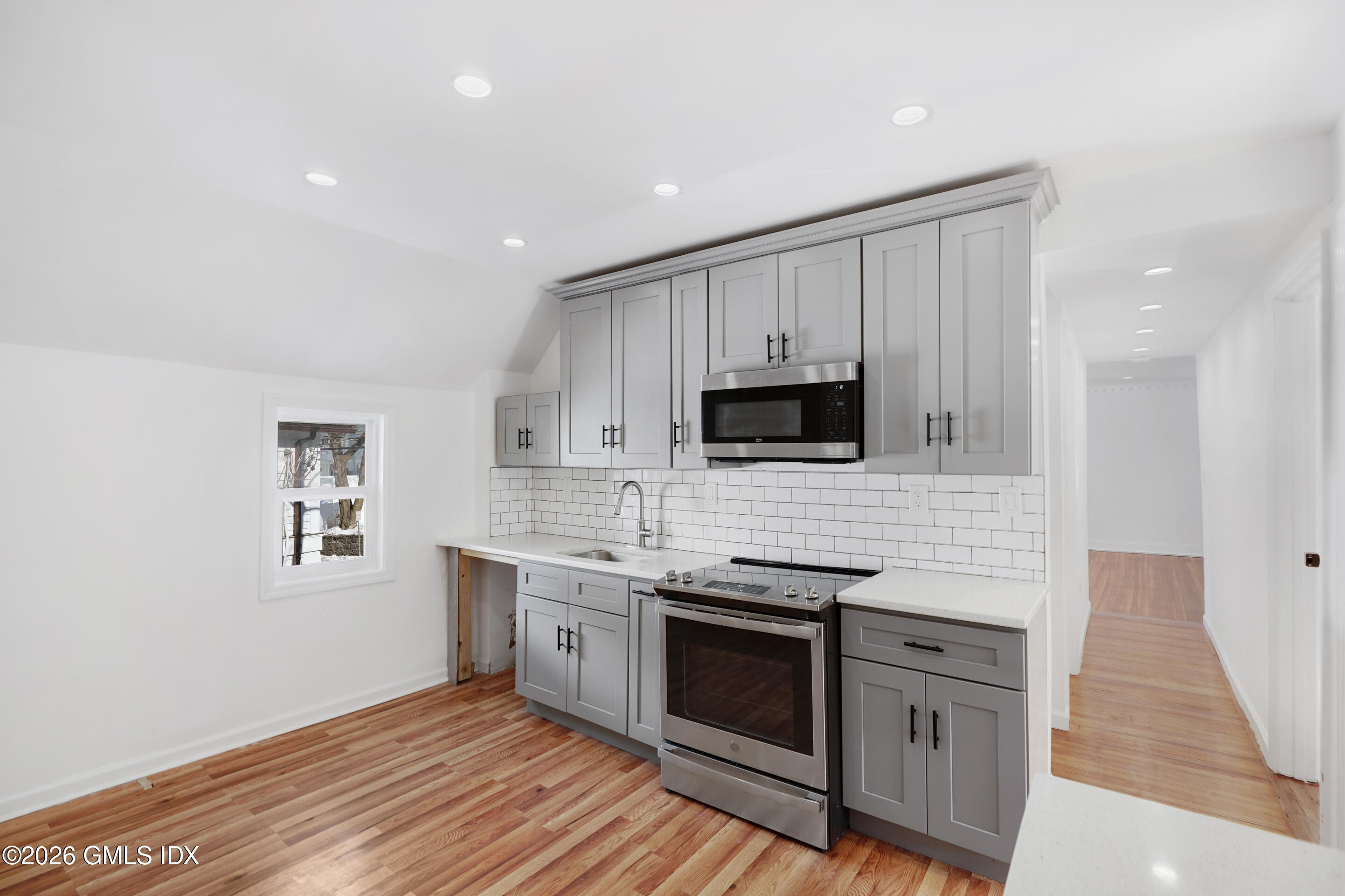 212 Davis Avenue, Unit B Greenwich, CT 06830 - Photo 6 of 10 a kitchen with stainless steel appliances a stove top oven a sink a refrigerator white cabinets and wooden floor