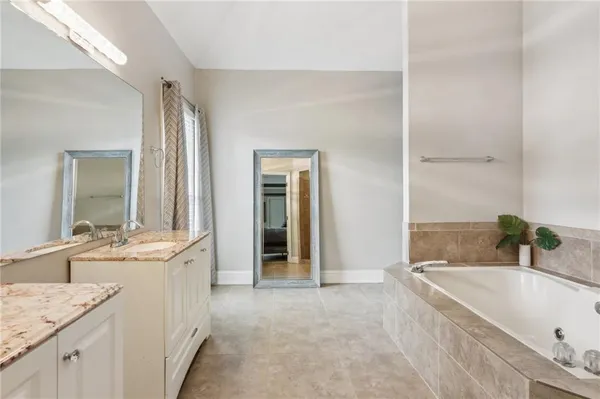 a bathroom with a granite countertop tub sink and mirror