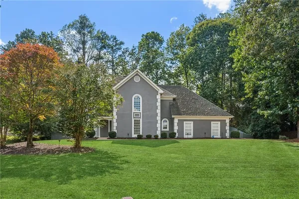a view of a yard in front of a house with large trees