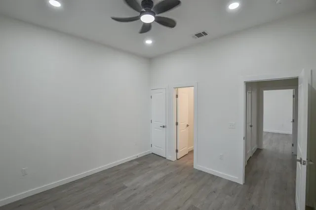 an empty room with wooden floor and a ceiling fan