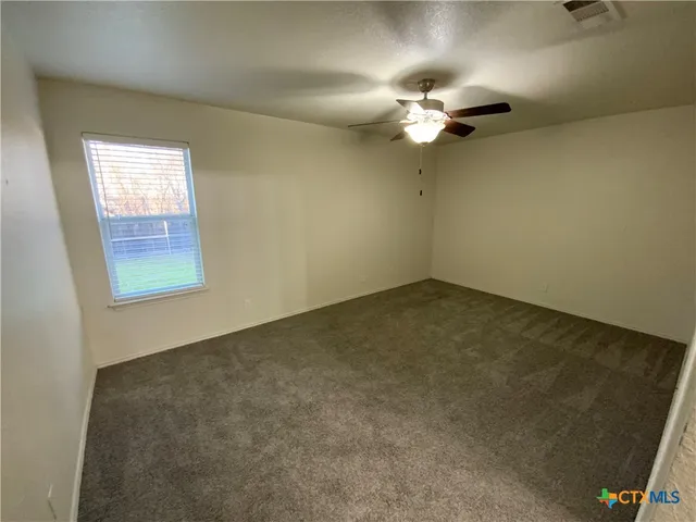 an empty room with windows and fan