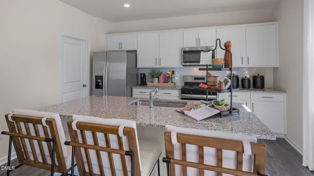a kitchen with granite countertop a table chairs microwave and refrigerator