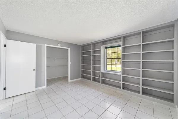 a view of an empty room with shelves and a window