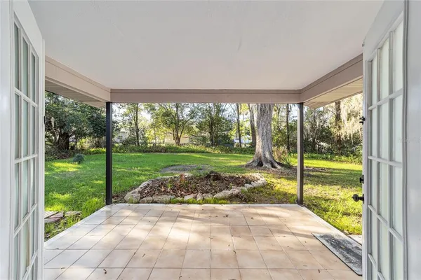 a view of yellow house with a yard and potted plants