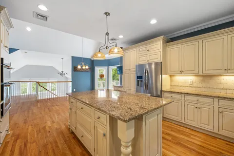 a kitchen with kitchen island granite countertop a stove a sink a center island and wooden floor
