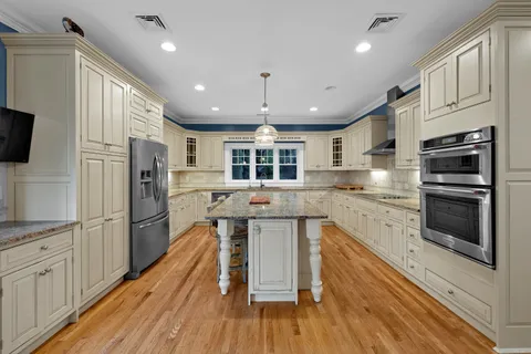 a large kitchen with stainless steel appliances kitchen island a large counter top space a refrigerator cabinets and a window