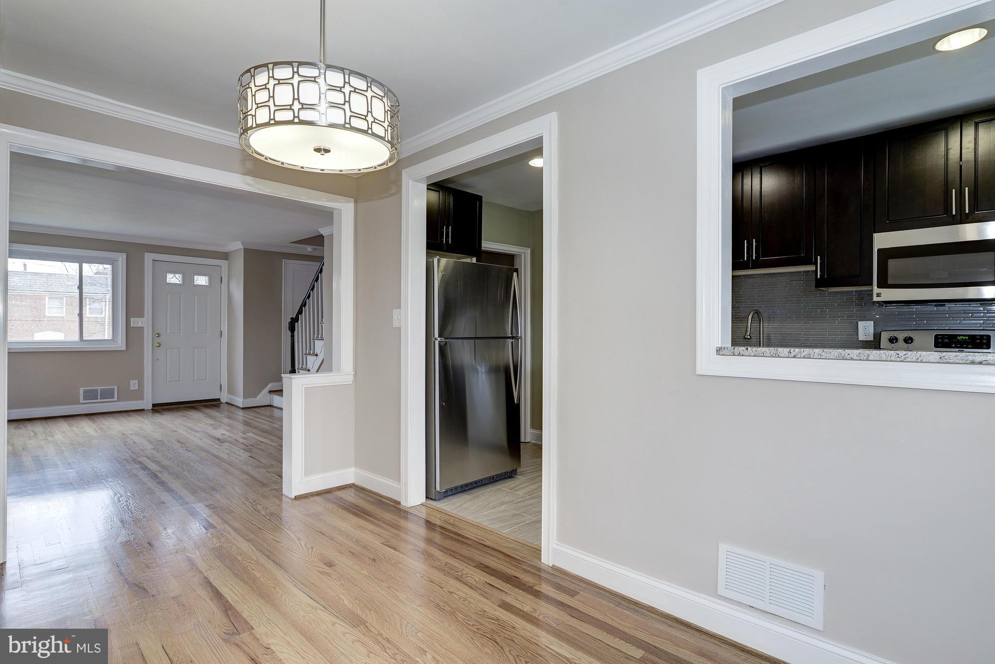 938 Coleridge Road Baltimore, MD 21229 - Photo 8 of 27 an empty room with wooden floor chandelier and windows