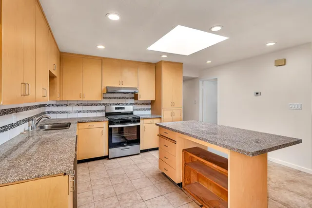 a kitchen with stainless steel appliances granite countertop a stove a sink and a microwave