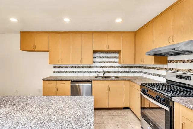 a kitchen with stainless steel appliances granite countertop a stove a sink and a microwave