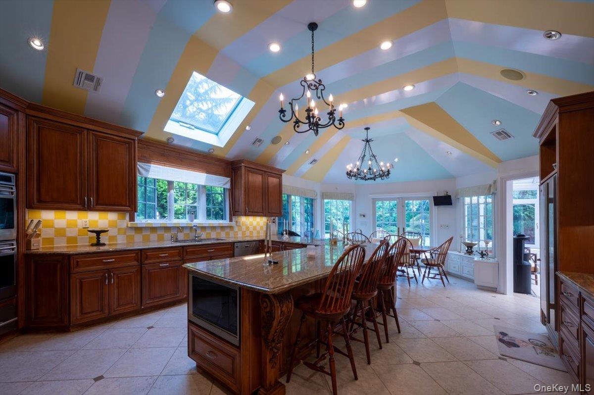 1331 Harbor Road Hewlett, NY 11557 - Photo 16 of 50 Kitchen with tasteful backsplash, a kitchen bar, a chandelier, dark stone countertops, and light tile patterned floors