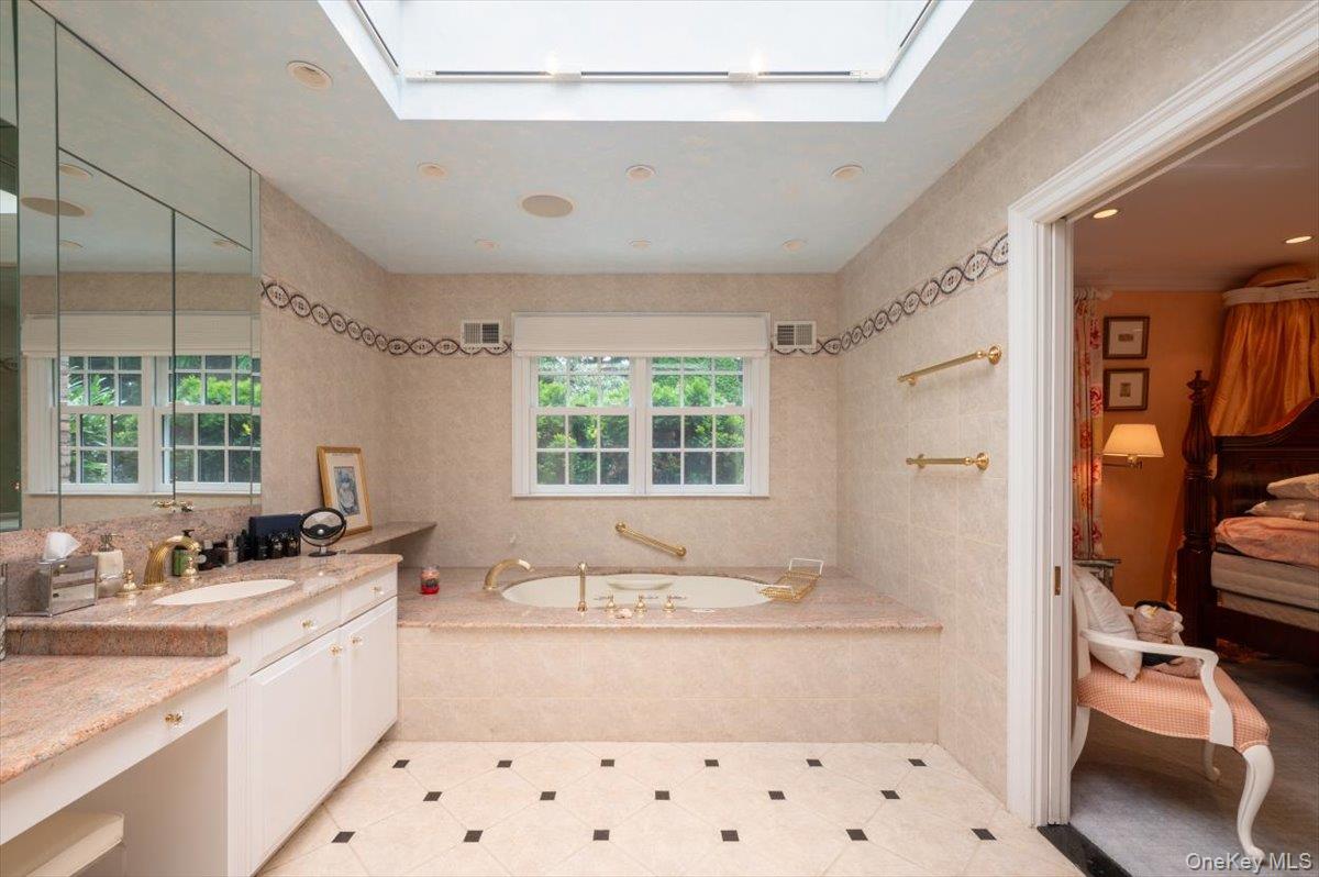 1331 Harbor Road Hewlett, NY 11557 - Photo 20 of 50 Full bathroom featuring a skylight, tile walls, vanity, a garden tub, and tile patterned floors