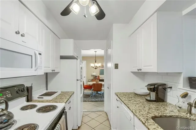 a kitchen with granite countertop a sink a stove and white cabinets