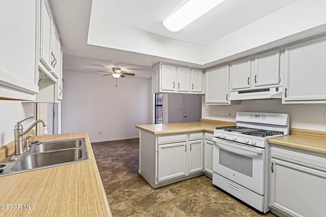 a kitchen with cabinets a sink and white appliances