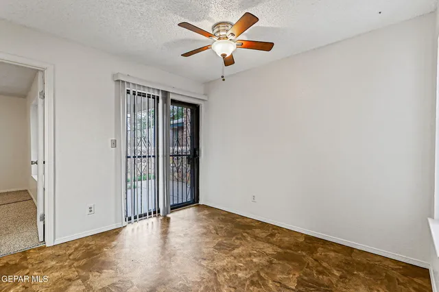 an empty room with windows and fan