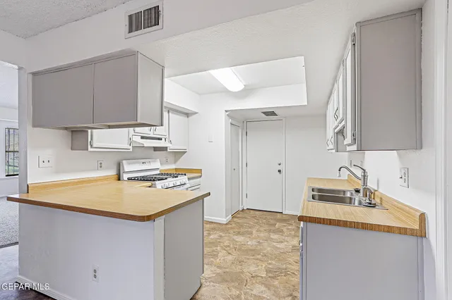 a kitchen with granite countertop a sink a stove and refrigerator