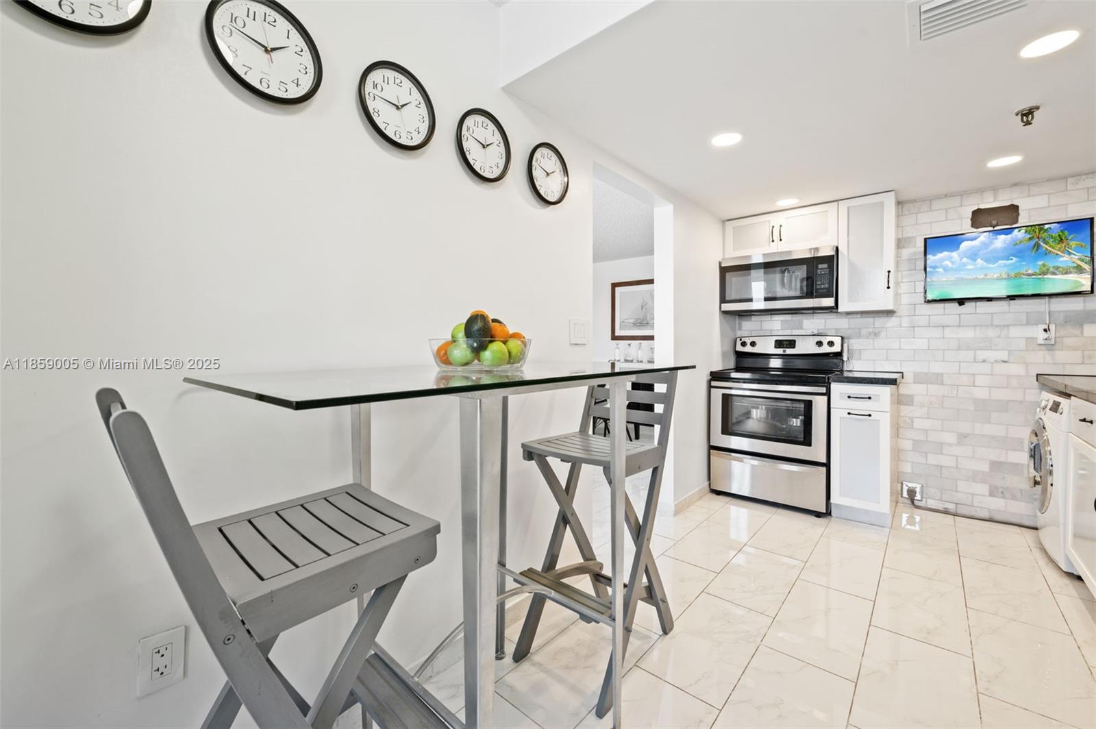 17890 West Dixie Highway, Unit 603 Miami, FL 33160 - Photo 13 of 34 a kitchen with stainless steel appliances granite countertop a chairs a stove a microwave and a refrigerator