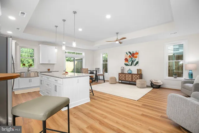 a large white kitchen with a stove a couch a dining table and chairs with wooden floor