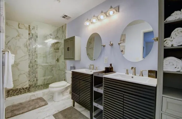 a bathroom with a double vanity sink toilet mirror and shower
