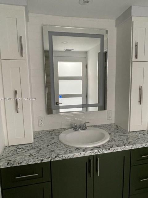 9225 Collins Avenue, Unit 1407 Surfside, FL 33154 - Photo 4 of 7 a bathroom with a granite countertop sink and a mirror