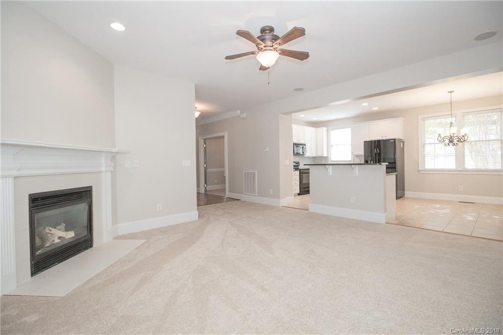 1376 Barnett Woods Fort Mill, SC 29708 - Photo 19 of 34 a view of a livingroom with a fireplace a ceiling fan a kitchen microwave and a refrigerator
