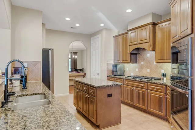 a large kitchen with kitchen island granite countertop a large counter top stainless steel appliances and cabinets