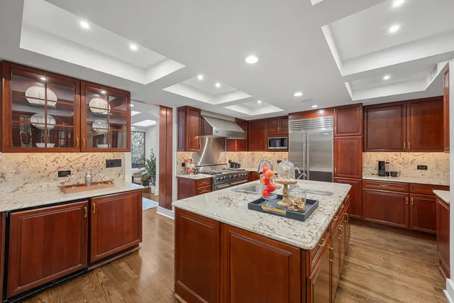 a kitchen with stainless steel appliances kitchen island granite countertop a sink refrigerator and cabinets