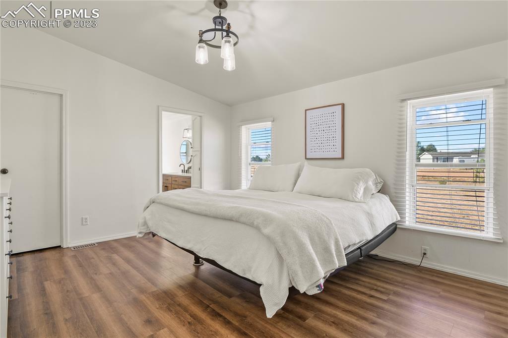 17755 Sage Crest Road Peyton, CO 80831 - Photo 18 of 37 a spacious bedroom with a bed and a chandelier