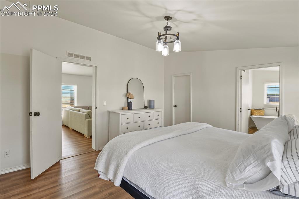 17755 Sage Crest Road Peyton, CO 80831 - Photo 19 of 37 a bedroom with a large bed and a chandelier