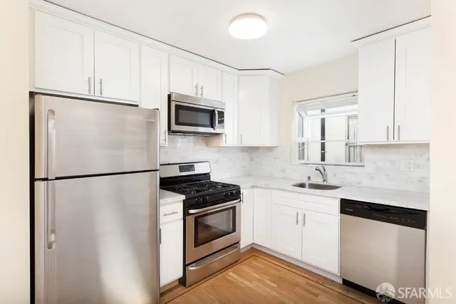 a white kitchen with stainless steel appliances a refrigerator sink and microwave