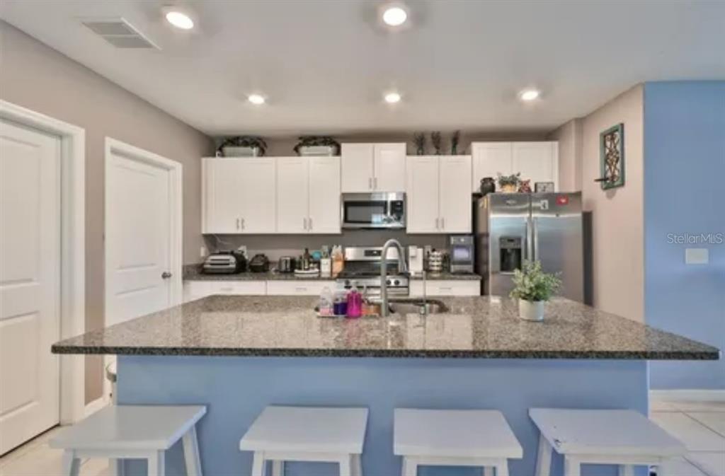 9317 Lemon Drop Loop Ruskin, FL 33573 - Photo 4 of 13 a kitchen with granite countertop a table chairs microwave and refrigerator