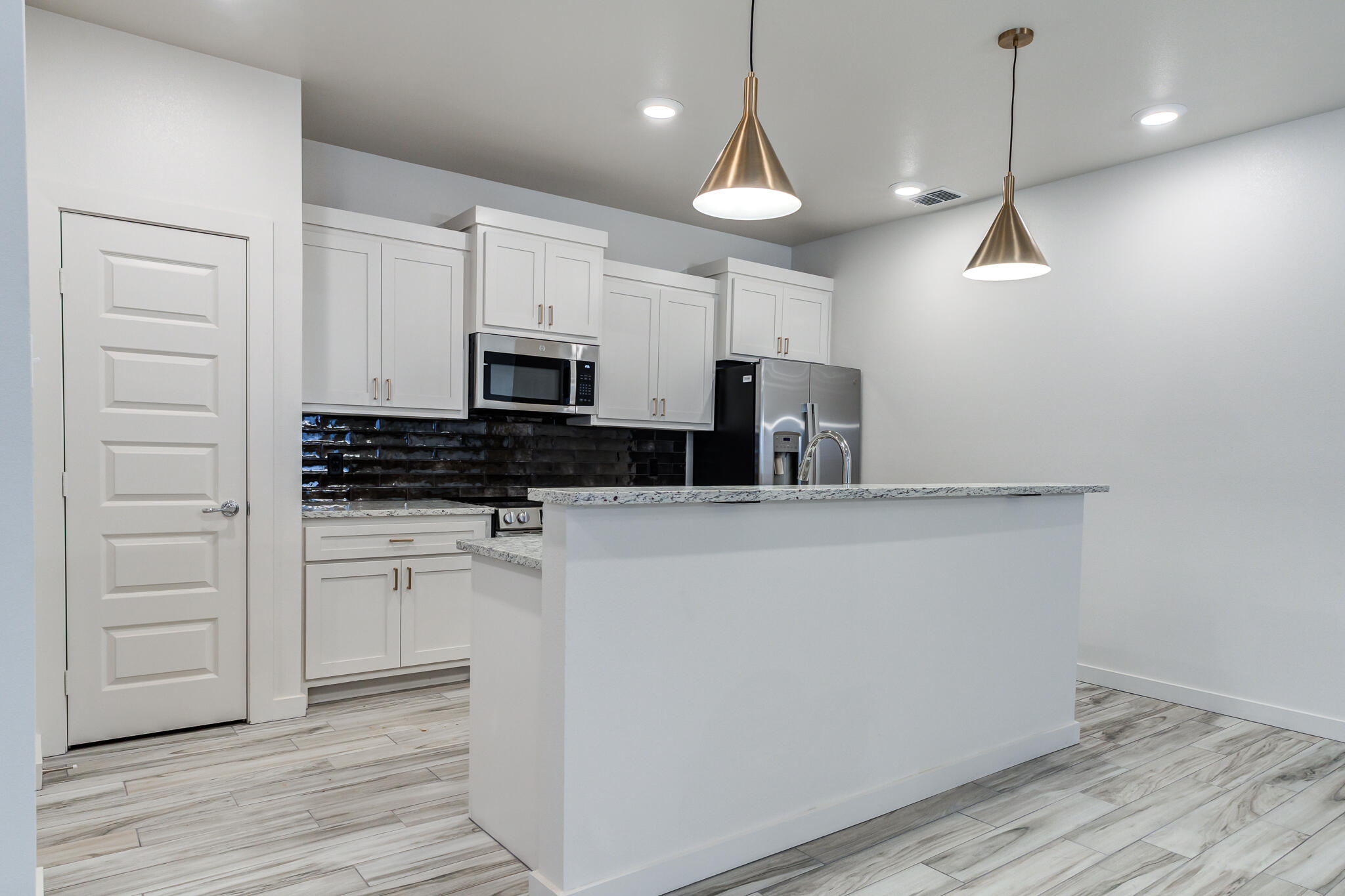 7044 41st Street Lubbock, TX 79407 - Photo 8 of 22 a kitchen with a refrigerator a stove and white cabinets with wooden floor