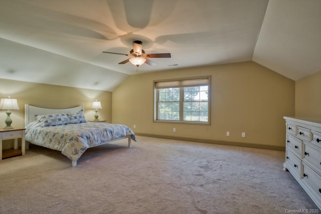 475 Gilbert Road Columbus, NC 28722 - Photo 28 of 45 a spacious bedroom with a bed and a chandelier