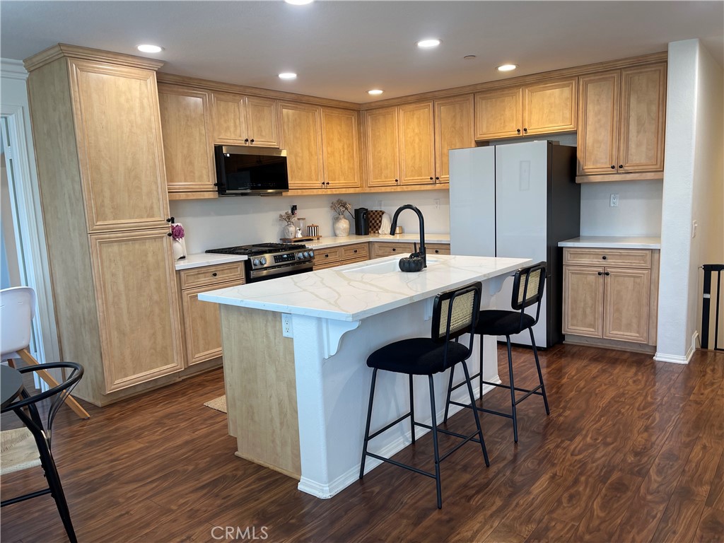 a kitchen with stainless steel appliances a refrigerator a stove a sink dishwasher and white cabinets with wooden floor