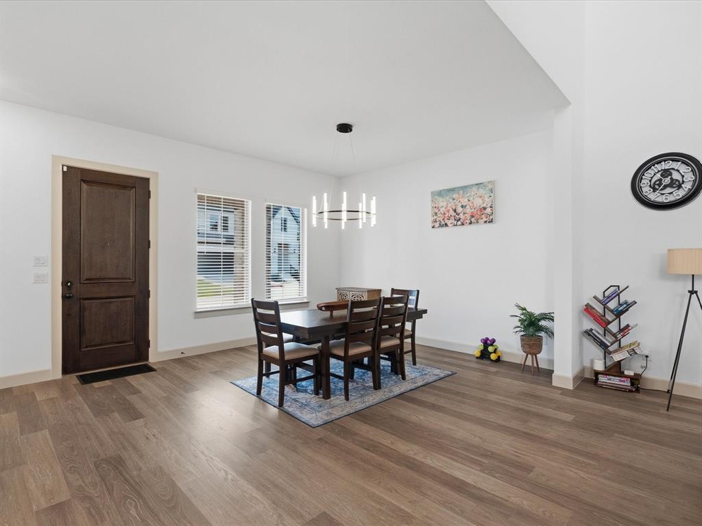 9533 Keep Street Frisco, TX 75035 - Photo 6 of 40 Dining area featuring wood-finish flooring, a contemporary linear chandelier, and ample natural light from two windows