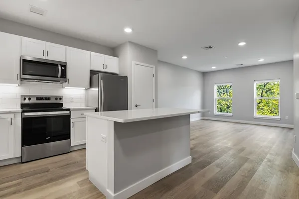 a kitchen with stainless steel appliances kitchen island granite countertop a stove a sink and a microwave