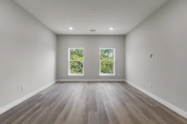 a view of an empty room with wooden floor and window